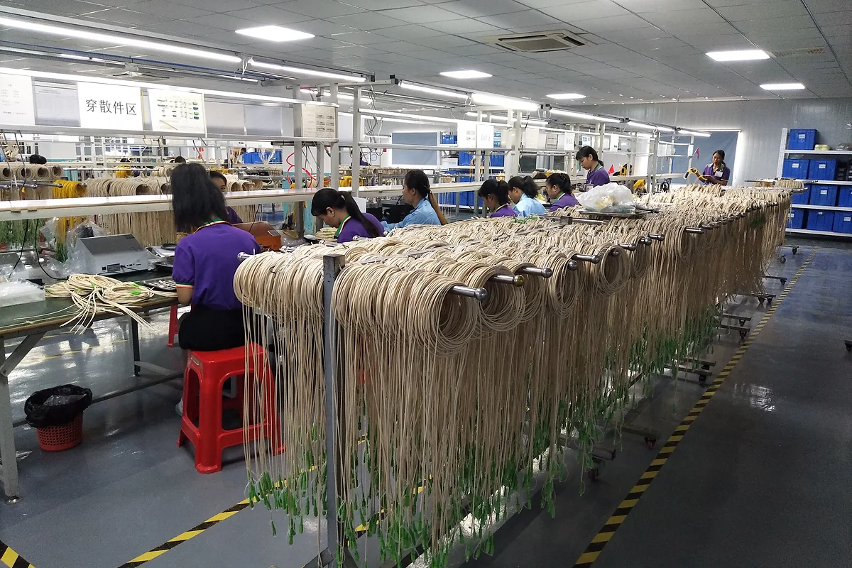 Workers assembling fiber optic patch cords on a production line